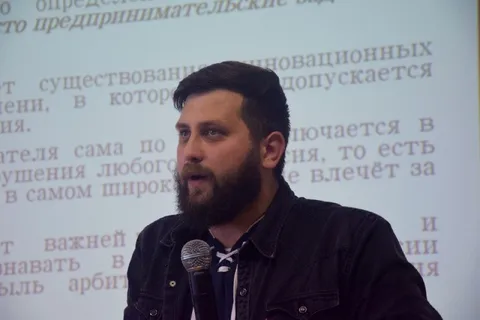 Лектор с микрофоном на фоне текста
