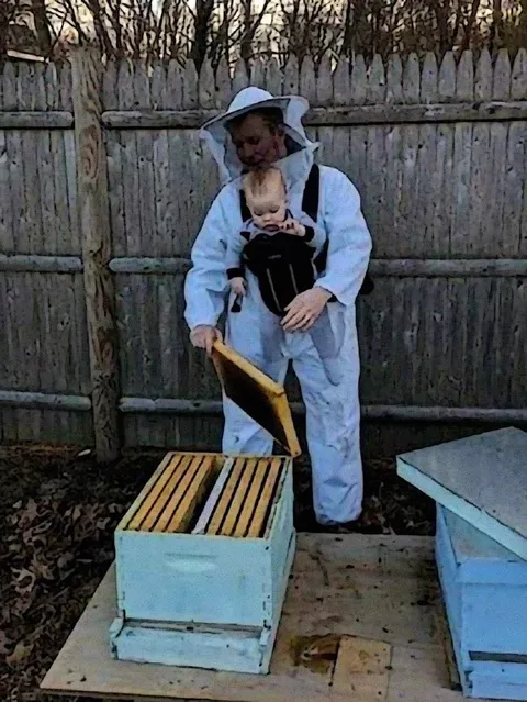 Пчеловод с младенцем у улья
