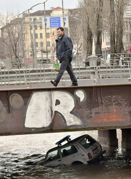 Мужчина идёт по утонувшей машине