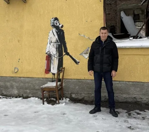 Мужчина рядом с рисунком Бэнкси