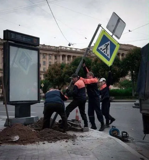 Рабочие поднимают знак