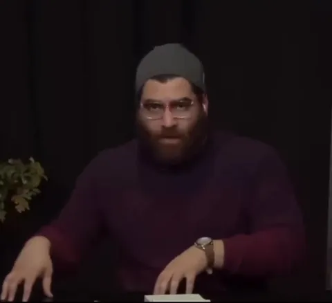 Бородатый мужчина молча смотрит