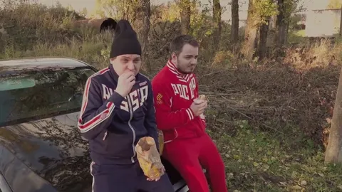 Два русских едят у машины