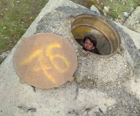 Мужчина вылезает из люка