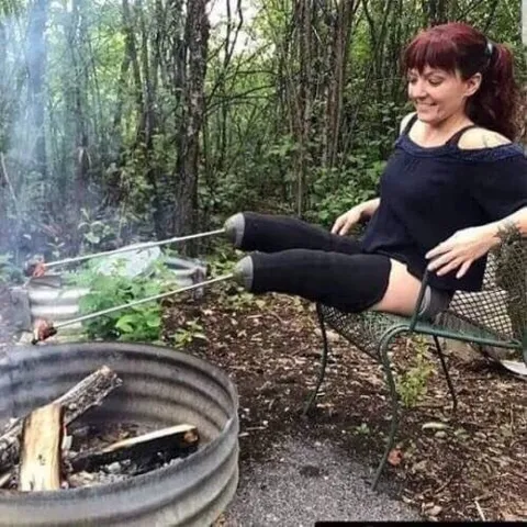Женщина греет ноги у костра