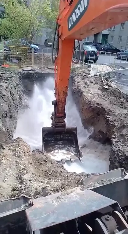 Экскаватор роет траншею с водой