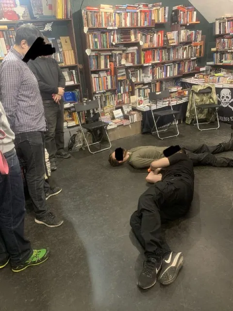 Люди лежат среди книжных полок