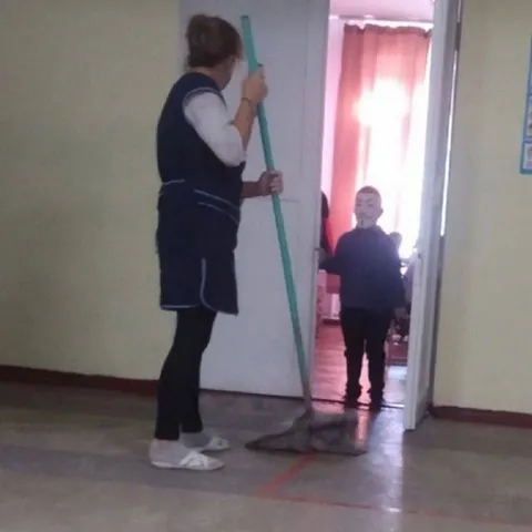 Уборщица моет дверь шваброй