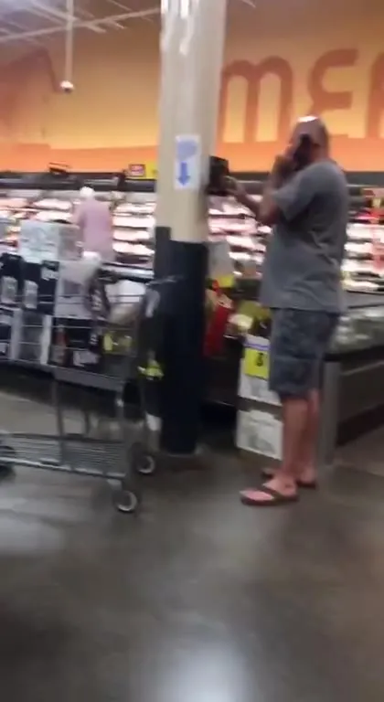 Man on the Phone in the Meat Aisle