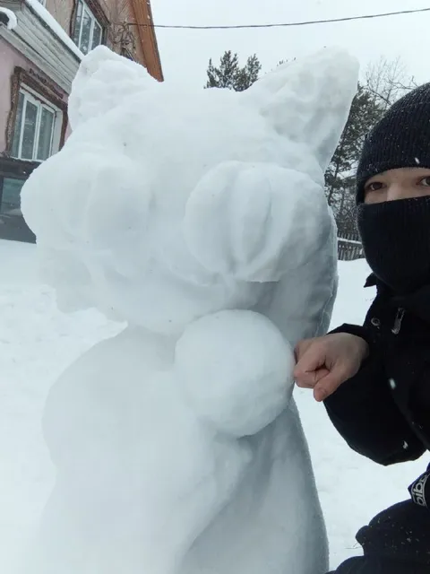 Снежная фигура и человек в балаклаве