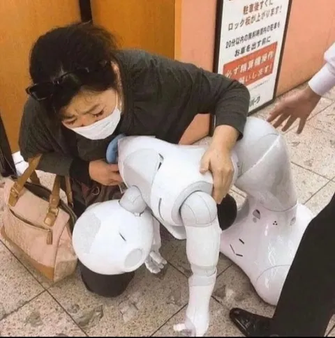 壊れたロボットを助ける女性