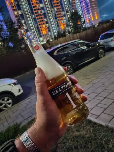 Балтика в руке на фоне города