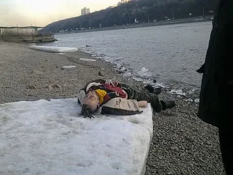 Человек лежит у реки на снегу