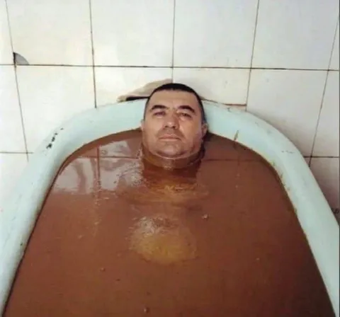 Мужчина в ванне с грязной водой
