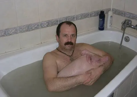 Мужчина обнимает свинью в ванной