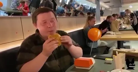 Мужчина жадно ест бургер