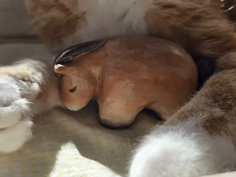 Кот обнимает деревянного зверька