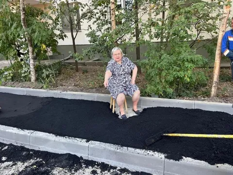 Бабушка сидит на новом асфальте