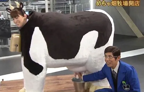 着ぐるみ牛を搾乳する男