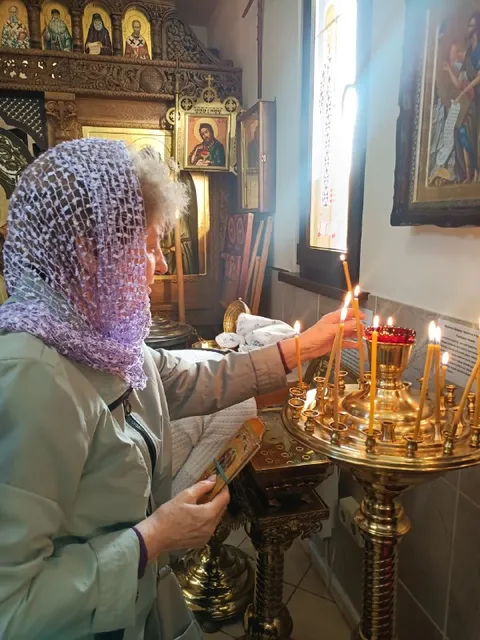 Бабушка ставит свечи в храме