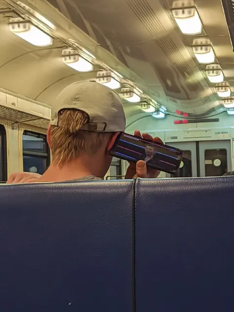 Мужчина смотрит телефон в метро