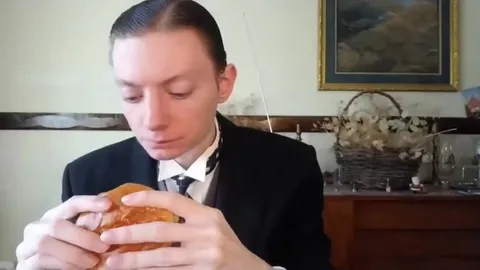 Человек в костюме ест бургер