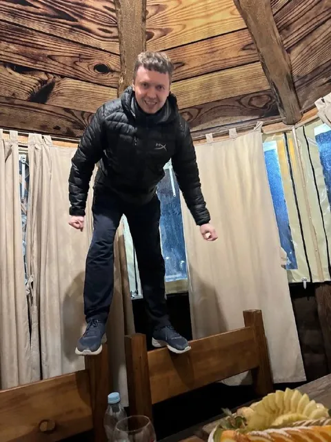 Мужчина стоит на спинке скамьи