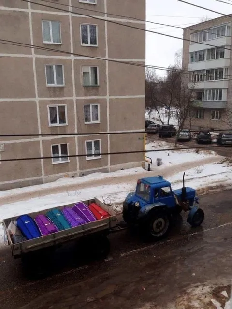 Трактор везёт разноцветные гробы
