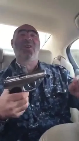 Мужчина с пистолетом смеётся в машине