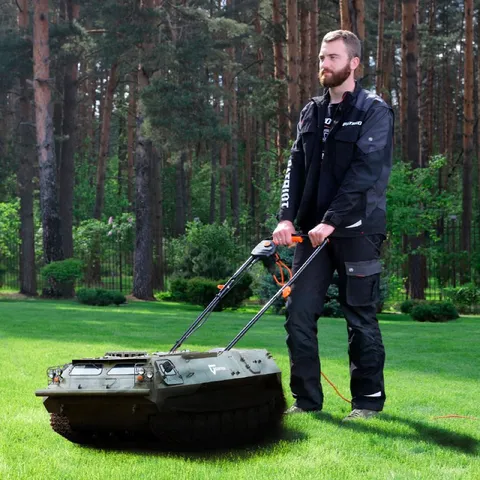Мужчина косит газон танком