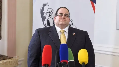 Мужчина перед множеством микрофонов