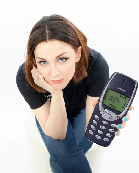 Девушка показывает старую Nokia